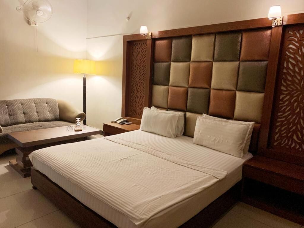 Una habitación de hotel con una cama grande, un sofá, una mesita de noche y una lámpara.