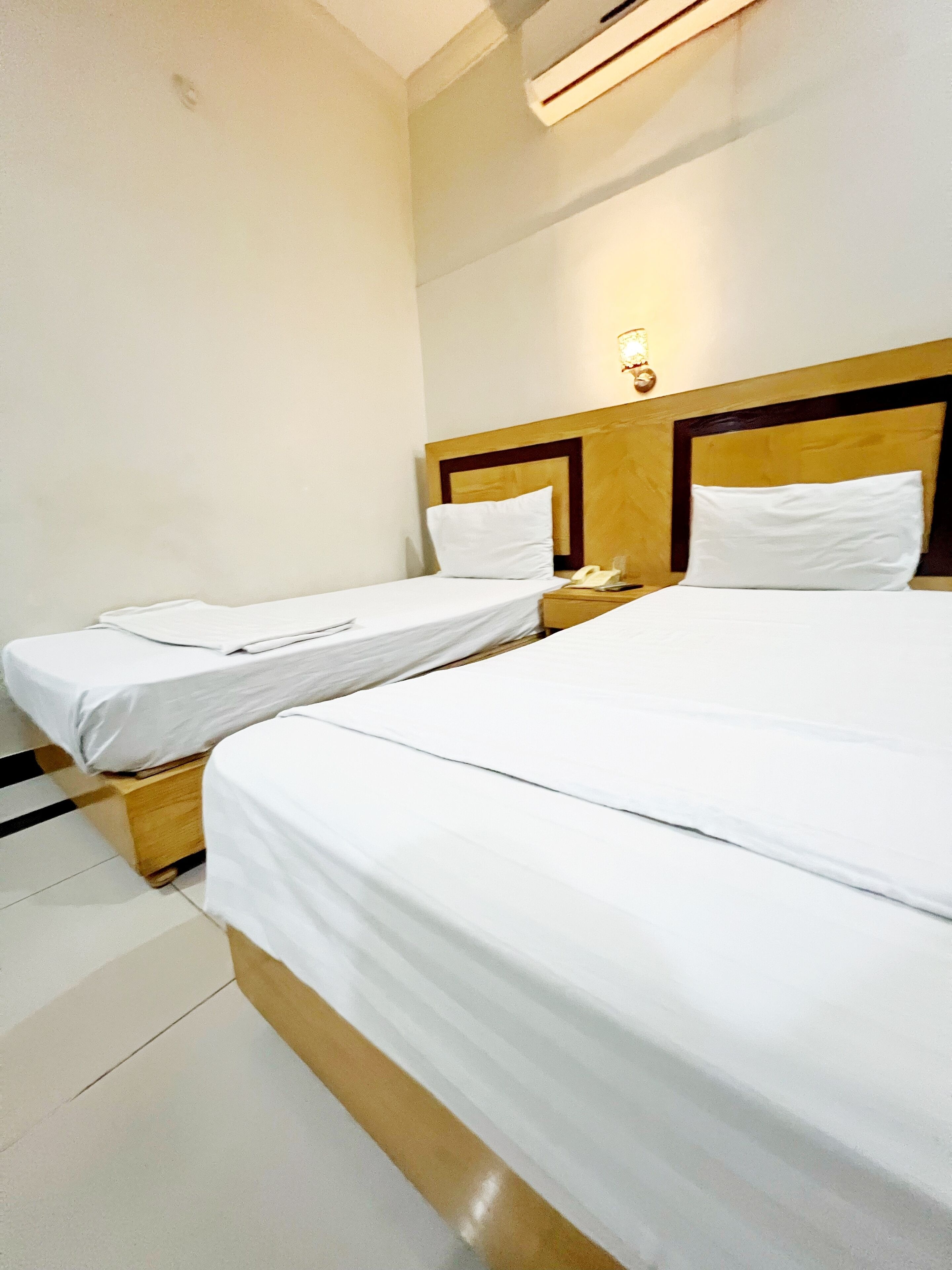 A hotel room with two single beds and a larger bed.
