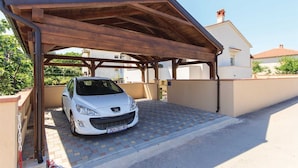 Ein weißes Auto steht unter einer überdachten Tiefgarage mit Fliesenboden.