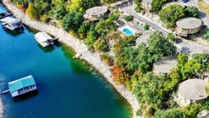 Vue aérienne d’une propriété au bord du lac, avec plusieurs maisons, un quai où sont amarrés des bateaux et une piscine.