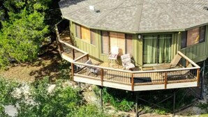Une maison à deux étages avec un balcon, une petite terrasse et une cheminée.