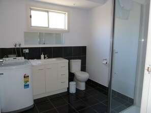 A modern bathroom with a toilet, sink, and washing machine. - Opposite Beaches - Short Walk to Shops & Eateries (Bridport)