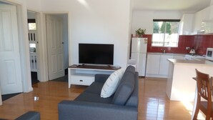 Una sala de estar moderna con un sofá gris, un televisor de pantalla plana y una mesa de centro de madera.