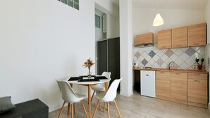 A compact kitchen with wooden cabinets, a tiled backsplash, and a dining area with a table and chairs.