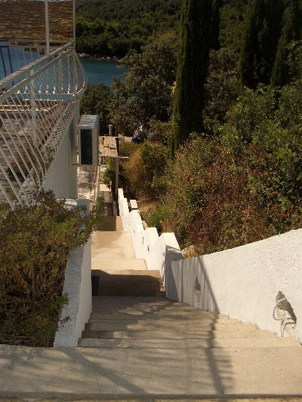 A staircase leading down to a beach with white walls and a metal railing.