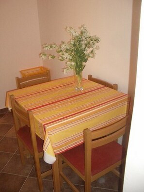 A dining table with a striped tablecloth, surrounded by wooden chairs with red cushions.