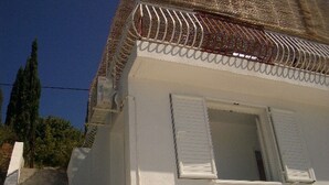 Um edifício branco com uma escadaria que leva a uma porta com persianas brancas.