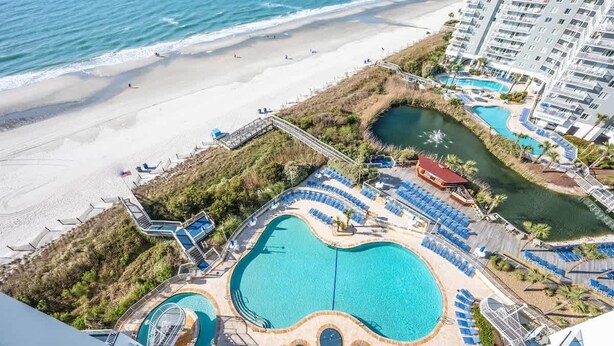 A resort with multiple swimming pools, a beach, and a high-rise building. - New High Floor, Direct Sea Watch, King Bed, Decor! (Myrtle Beach)