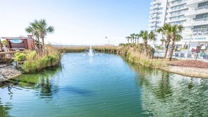 A water canal with a fountain, surrounded by palm trees and a building labeled "SOUTH TOWER". - New High Floor, Direct Sea Watch, King Bed, Decor! (Myrtle Beach)