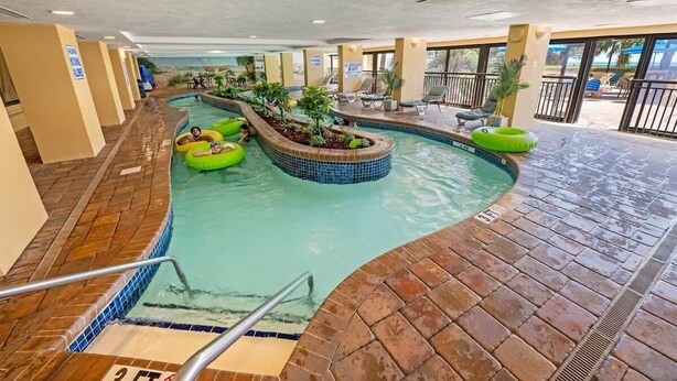 Un espace piscine intérieure doté de plusieurs couloirs de nage, de chaises longues et d’un petit jacuzzi.