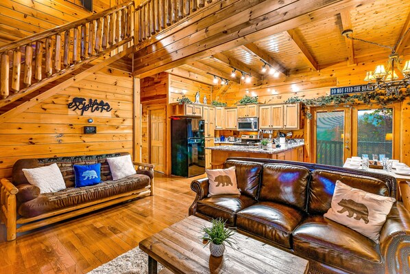Een houten chalet van binnen met een woonkamer, keuken en eethoek.