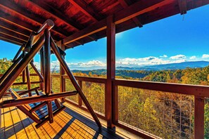 A wooden deck with a swing, overlooking a forested valley with mountains in the distance. - 🏔🏔 180° Views 🏔🏔 ❸Decks ❸Masters ❷Game R♨Hot T (Sevierville)