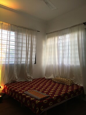 A bedroom with a bed, curtains, and a window. - Inside the heart of Kokrobite, we're an art house for artists and art lovers.... (Kokrobite)