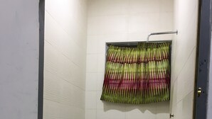 Pieni, laatoitettu suihkuhuone, jossa on kuviollinen suihkuverho ja laatoitettu lattia.