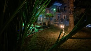 A nighttime view of a building with a pool, surrounded by palm trees. - Greenway Hotel (Fethiye)