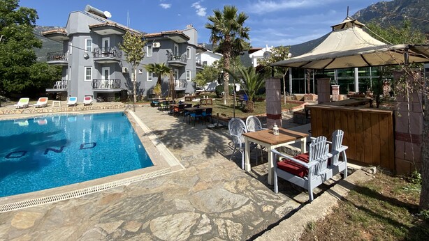 A pool area with lounge chairs, a dining table, and a gazebo. - Greenway Hotel (Fethiye)