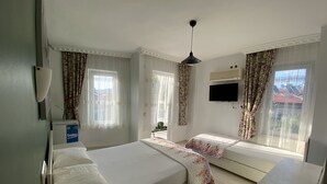 A hotel room with two beds, a TV, and a window with curtains. - Greenway Hotel (Fethiye)