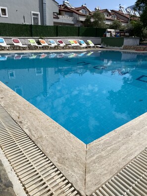 Una piscina con sillas de descanso y un suelo de hormigón.