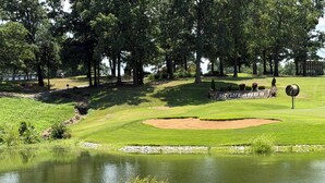 A golf course with a pond, sand bunkers, and a sign that reads 'HIGHLANDS'.