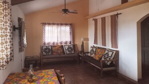 A dining area with a table set for two, a ceiling fan, and a sofa with patterned cushions. - Corner of punta pequena/fredrico (San Juanico)