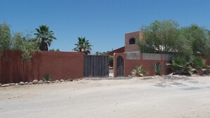 Un paysage désertique avec un bâtiment caractérisé par un mur rouge, une petite tour et une porte.