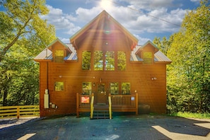 A wooden cabin with a front porch, a set of stairs leading to the entrance, and a clear sky above.