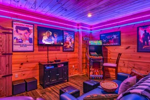 A cozy room with wooden walls, a large TV, and a gaming machine.