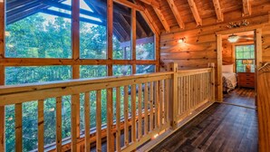Een houten chalet met een balkon met uitzicht op een bos.