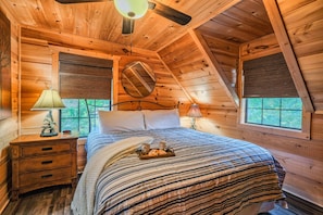 Une chambre confortable dans un chalet en bois, avec un lit, des tables de chevet et une fenêtre équipée de stores.