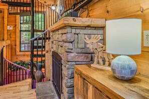 Un escalier en bois, avec un mur en pierre, une rampe en bois et une tête de cerf décorative.