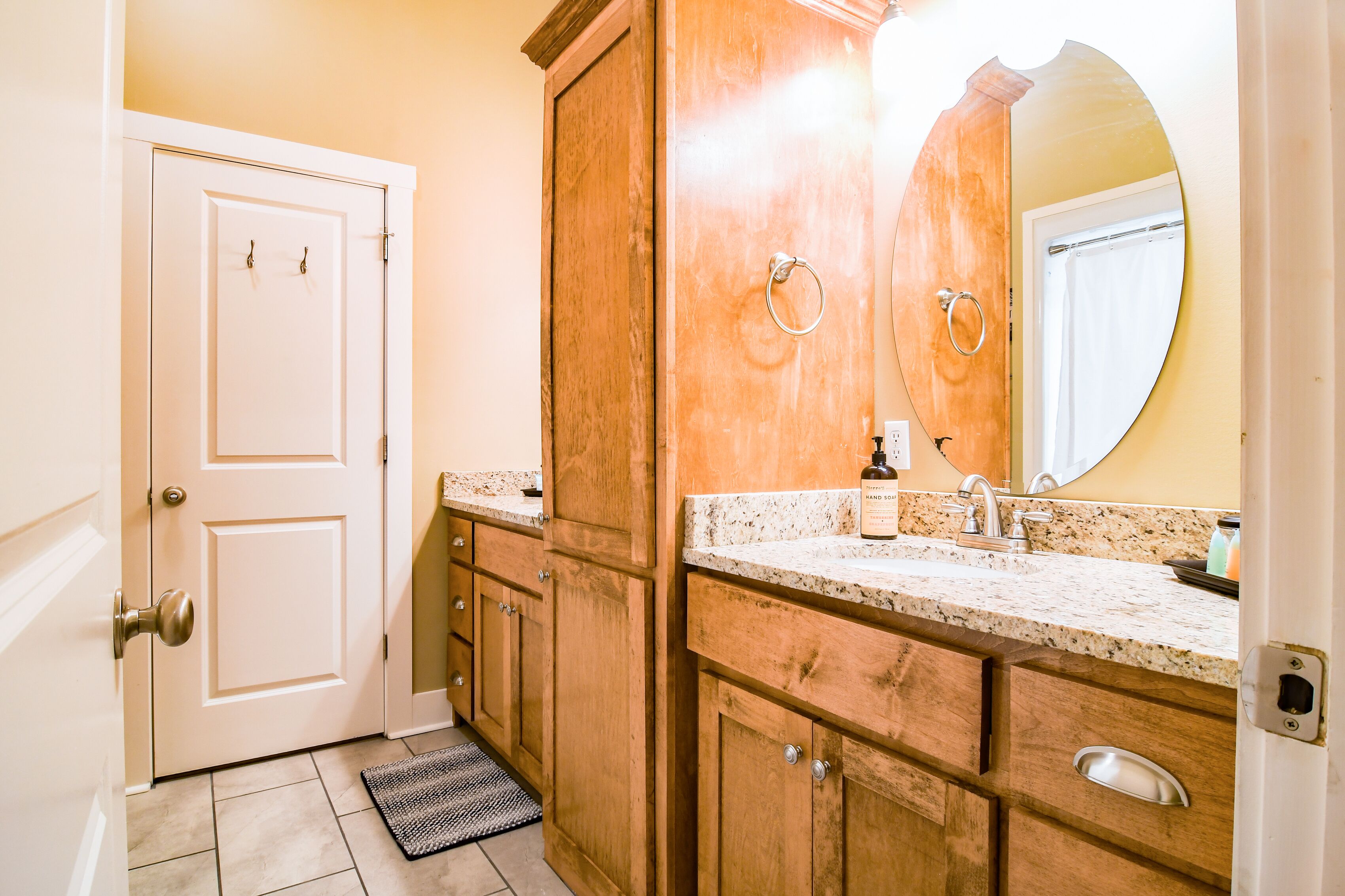 A bathroom with wooden cabinets, a marble countertop, a sink, and a mirror.