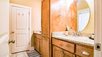 A bathroom with wooden cabinets, a marble countertop, a sink, and a mirror.