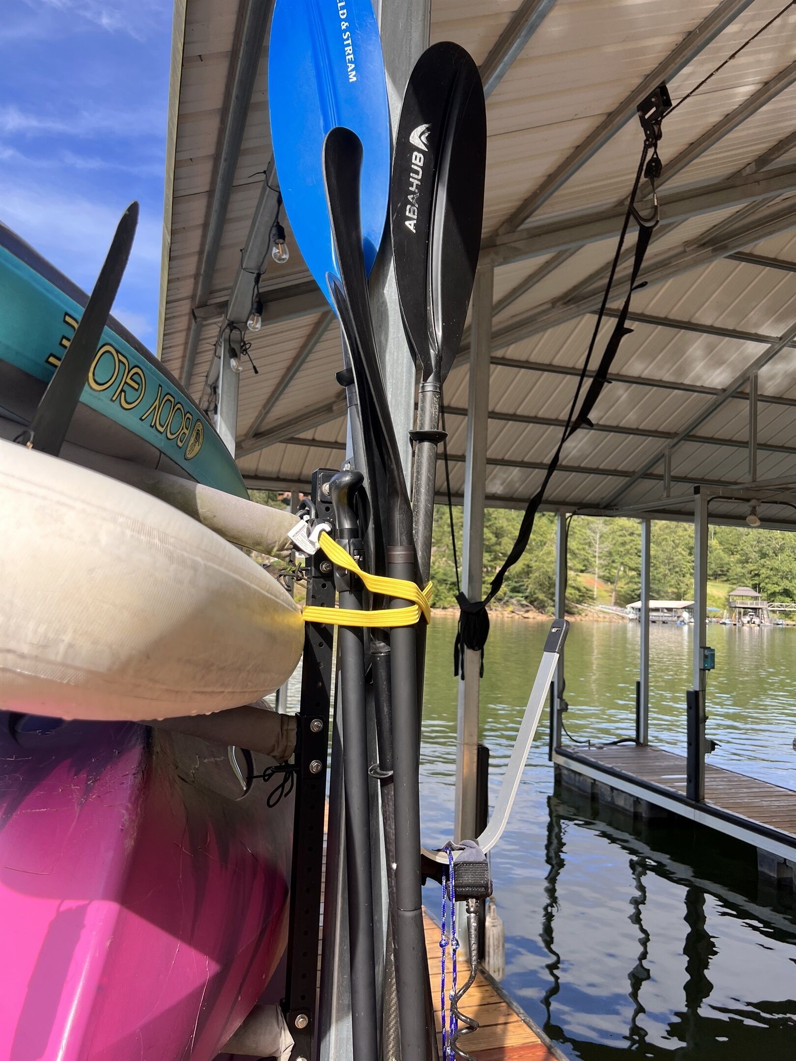 A kayak and paddle secured on a dock with a metal roof overhead.