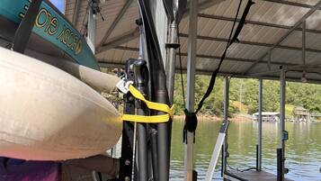 A kayak and paddle secured on a dock with a metal roof overhead.