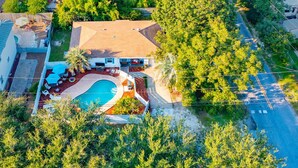 An aerial view of a house with a swimming pool, surrounded by trees and a road. - 5mins Steps to Beach | Fenced Heated Pool w/ Grill (Miramar Beach)