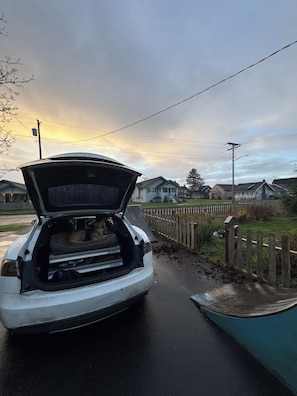 A car with its trunk open, revealing a dog and a pet bed inside.