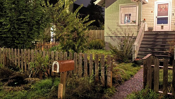 Una casa con cerca de madera, buzón y jardín.