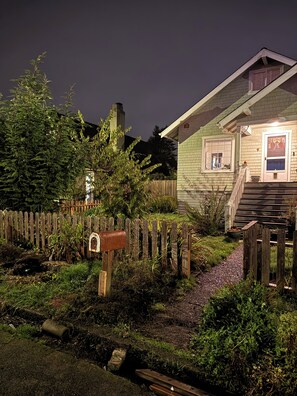 Une maison avec une clôture en bois, une boîte aux lettres et un jardin.