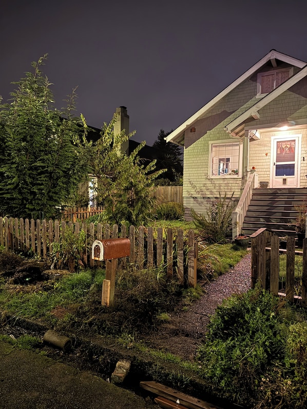 A house with a wooden fence, a mailbox, and a garden.