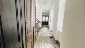 Un corridoio con pavimento decorato, porte in legno e vista su un'altra stanza.