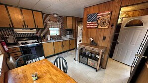Cocina con armarios de madera, una mesa de comedor y una pequeña barra.