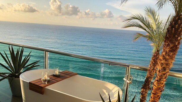 A private balcony with a white bathtub, a wooden deck, and a view of the ocean. - The Quarry Cancun- luxury oceanfront studio (Cancún)