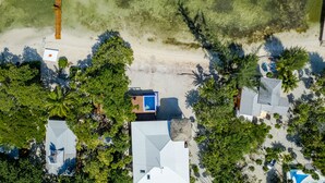 Ett flygbildsbild av ett bostadsområde med en swimmingpool, flera hus och frodig grönska.