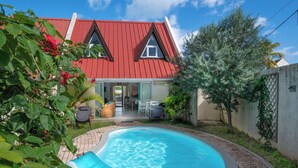 Una propiedad residencial con piscina, una casa con techo rojo y un área de patio.