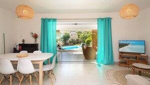 Una sala de estar moderna con comedor, televisor y vista a una piscina.
