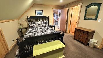 Een slaapkamer met een bed, een dressoir, een spiegel en een deur naar een andere kamer.