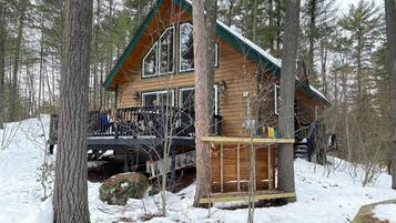 Een chalet met een houten gevel, een balkon en een besneeuwde omgeving.