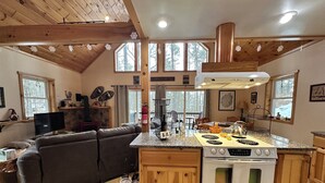 Une cuisine chaleureuse avec un îlot central en bois, un four encastré et un coin repas comprenant une table et des chaises.