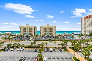 A hotel with a parking lot, a pool, and a view of the ocean.