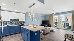 Una habitación de hotel moderna con cocina, comedor, sala de estar y un balcón con vista al océano.